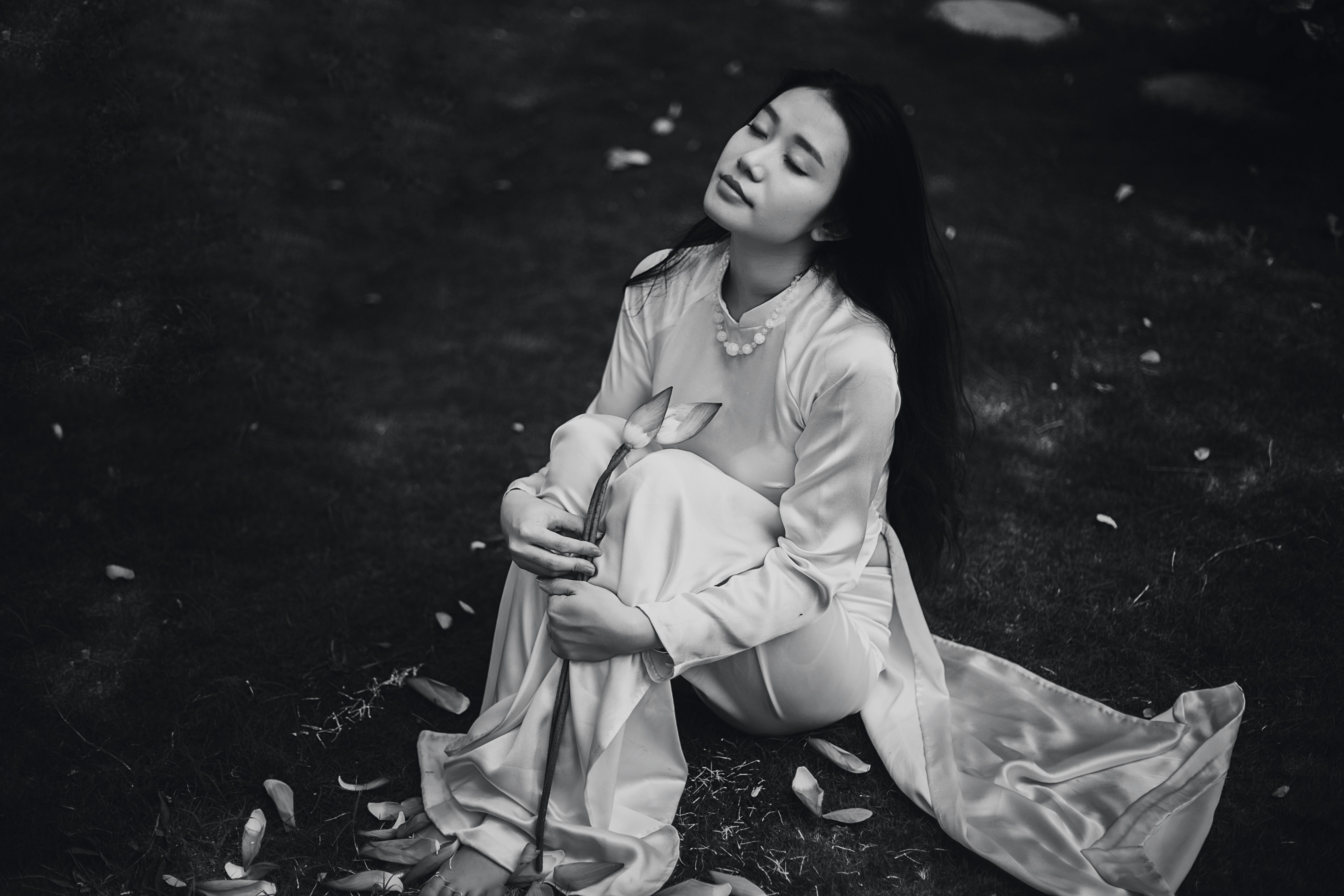 woman wearing white dress sitting on ground grayscale photo